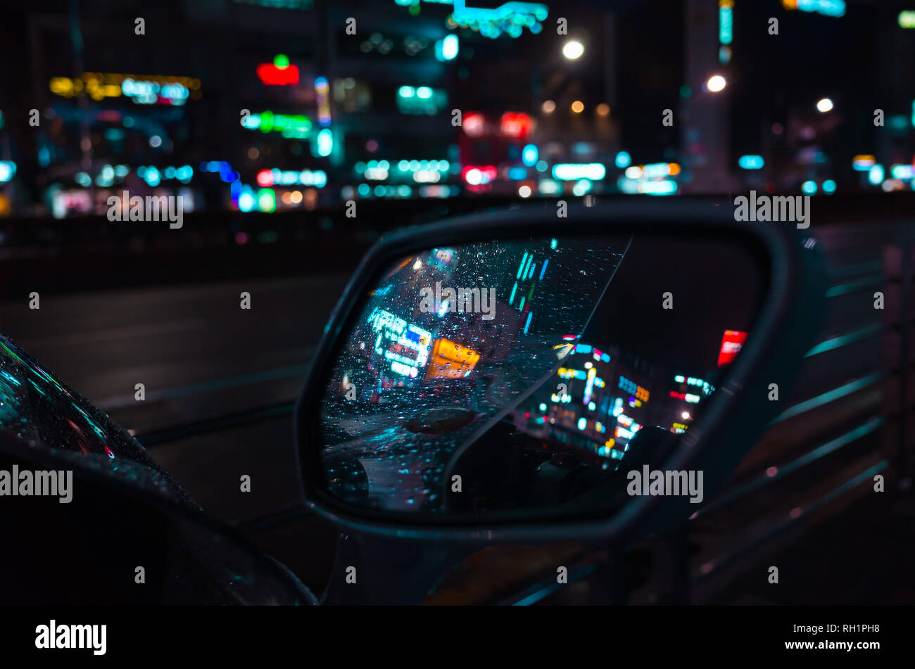 Abstract Night city unscharfen Hintergrund, bunte Reflexionen und Regentropfen auf nassen Auto Spiegel Stockfoto
