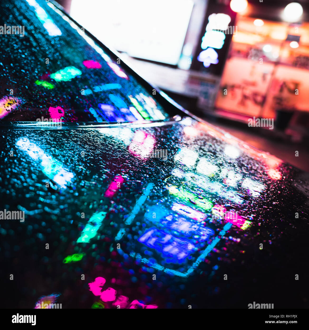 Bunte Reflexionen und Regentropfen auf nassen Auto Haube. Abstract Night City Square Hintergrund Stockfoto