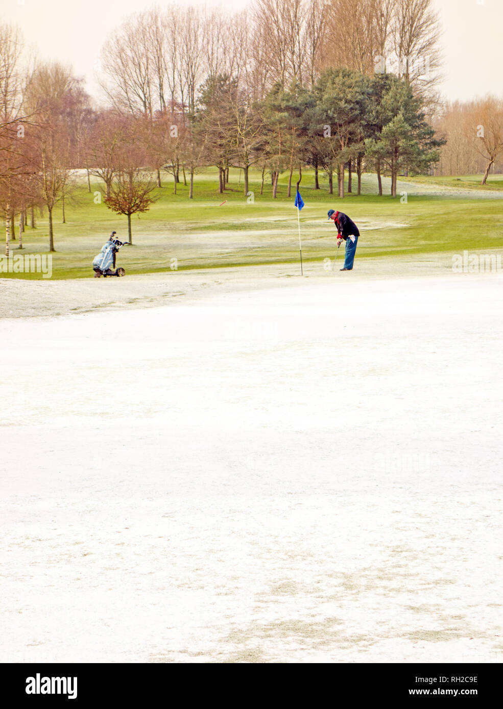 Mann spielt Golf im Winter auf Golf ein Kurs trotz Schnee und eisigen Temperaturen bei Malkins Bank in der Nähe von Sandbach Cheshire England Großbritannien Stockfoto