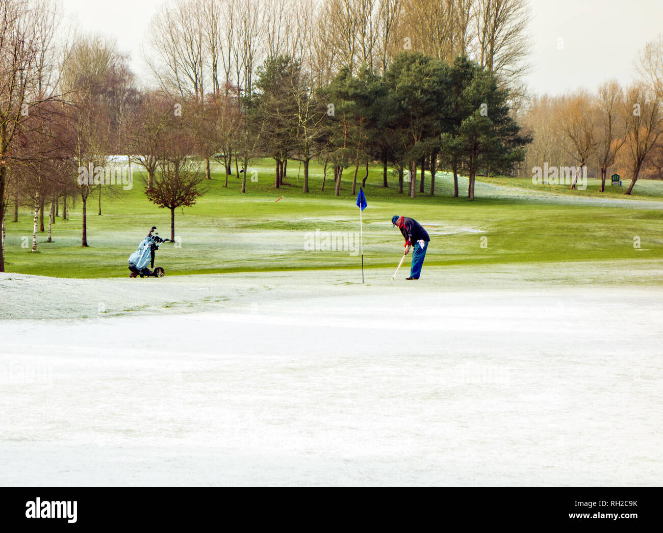 Mann spielt Golf im Winter auf Golf ein Kurs trotz Schnee und eisigen Temperaturen bei Malkins Bank in der Nähe von Sandbach Cheshire England Großbritannien Stockfoto