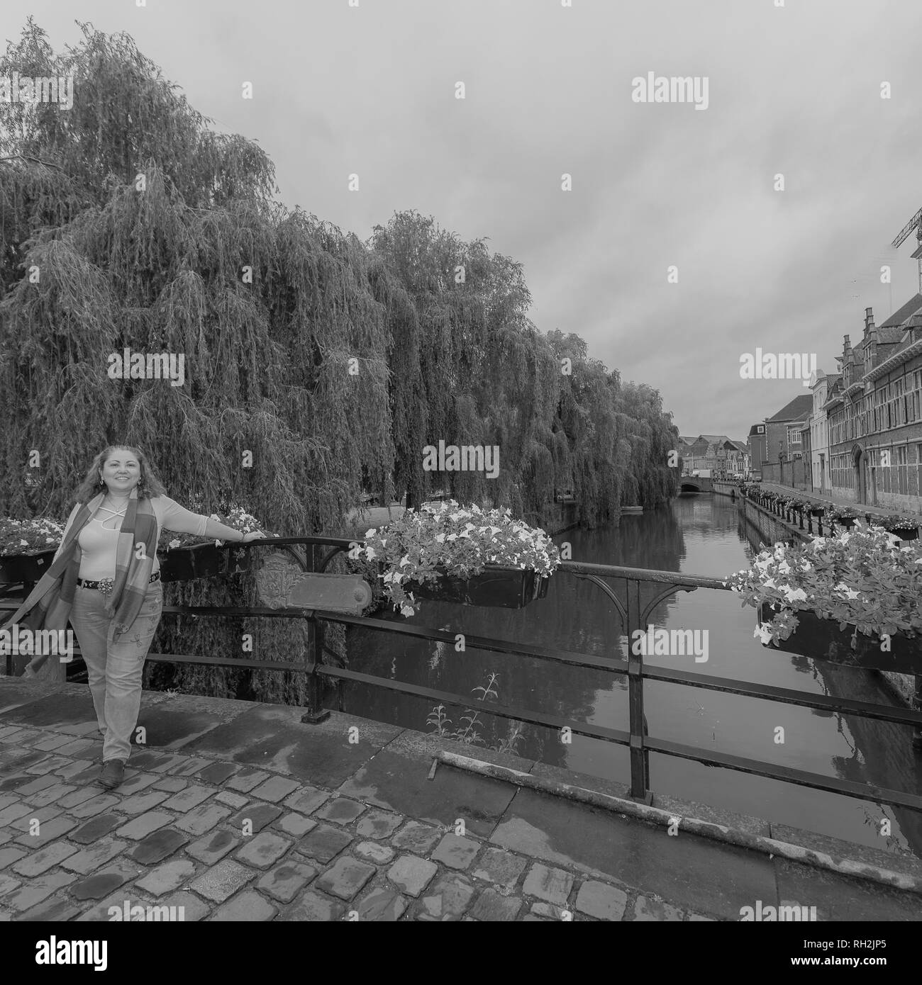 Latin Frau lehnte sich auf einen Metallzaun auf einer Brücke mit einem Kanal im Hintergrund in der Stadt Gent, Belgien an einem Tag bereisen und die Stadt genießen Stockfoto