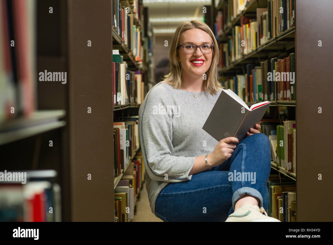 Ein erstes Jahr Bachelor Studentin, Universität Aberystwyth, Wales UK - lesen Ihren Text Bücher in der Bibliothek auf dem Campus der Hochschule Stockfoto