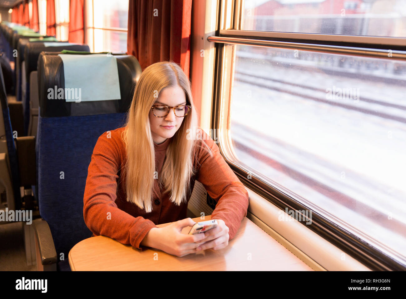 Junge Frau mit Handy in Zug Stockfoto