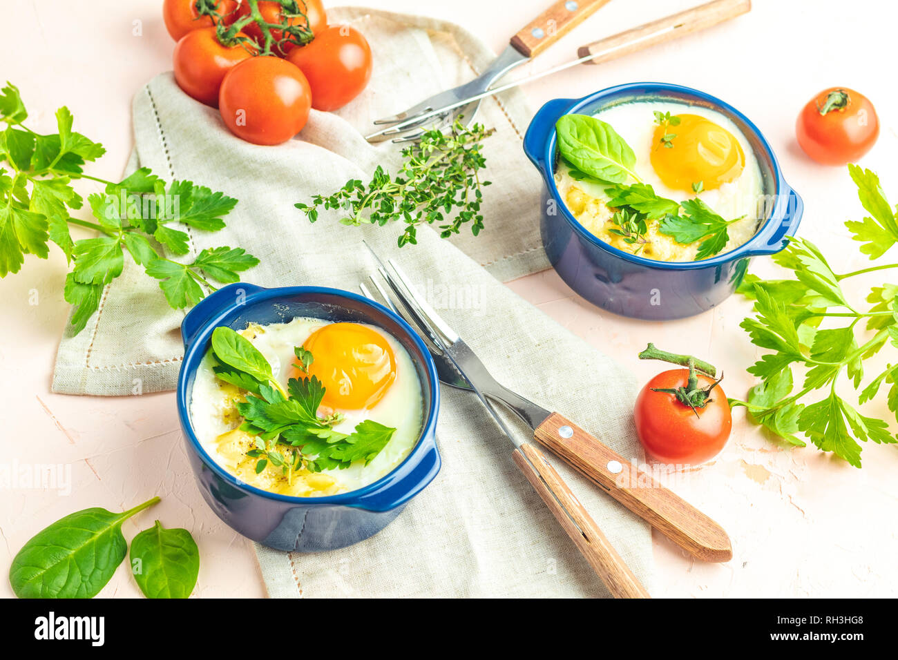 Eier kokot Cocotte französisches Frühstück. Gebackene Eier in blau Keramik Backformen. Portioniert Auflauf aus Gemüse und Eier im italienischen Stil. Stockfoto