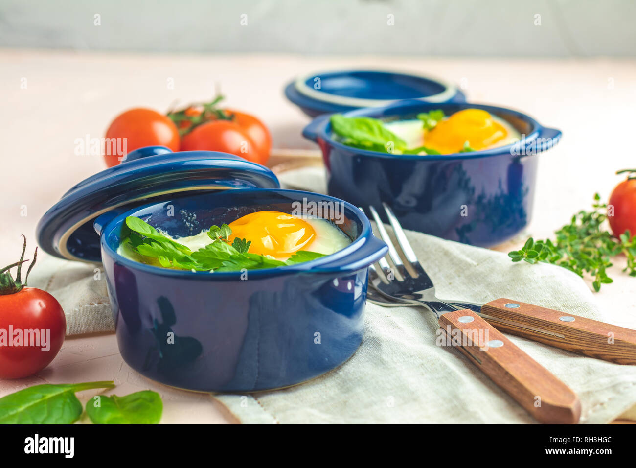 Eier kokot Cocotte französisches Frühstück. Gebackene Eier in blau Keramik Backformen. Portioniert Auflauf aus Gemüse und Eier im italienischen Stil. Stockfoto