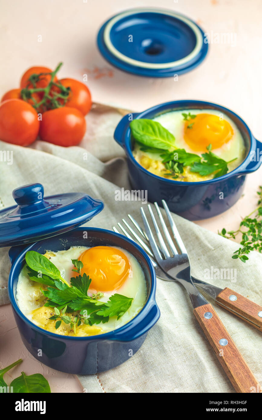Eier kokot Cocotte französisches Frühstück. Gebackene Eier in blau Keramik Backformen. Portioniert Auflauf aus Gemüse und Eier im italienischen Stil. Stockfoto