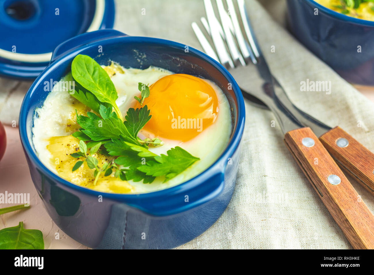 Eier kokot Cocotte französisches Frühstück. Gebackene Eier in blau Keramik Backformen. Portioniert Auflauf aus Gemüse und Eier im italienischen Stil. Stockfoto