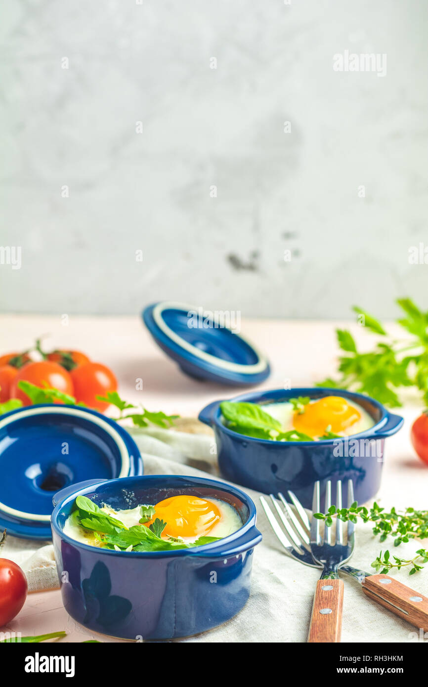 Eier kokot Cocotte französisches Frühstück. Gebackene Eier in blau Keramik Backformen. Portioniert Auflauf aus Gemüse und Eier im italienischen Stil. Stockfoto