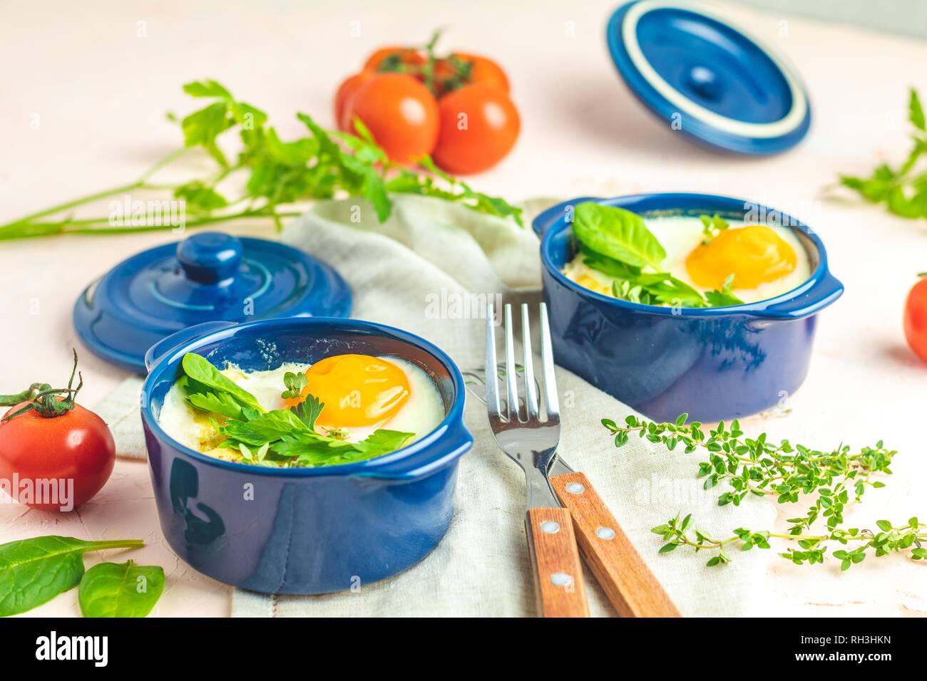 Eier kokot Cocotte französisches Frühstück. Gebackene Eier in blau Keramik Backformen. Portioniert Auflauf aus Gemüse und Eier im italienischen Stil. Stockfoto