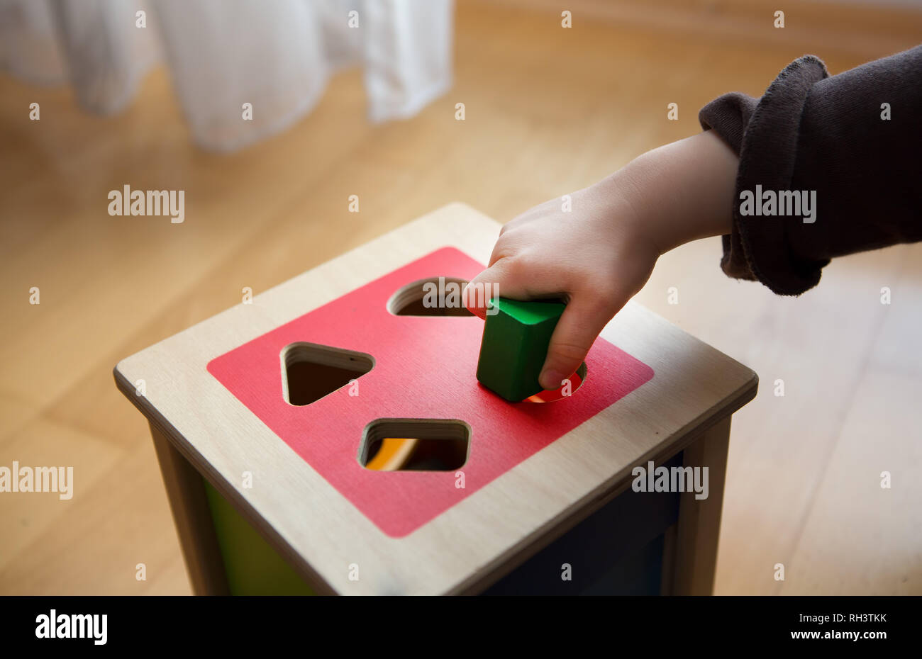 Kinder spielen mit Holz Steine in verschiedenen Formen und Farben, die versuchen, Sie in der richtigen Bohrung setzen Stockfoto