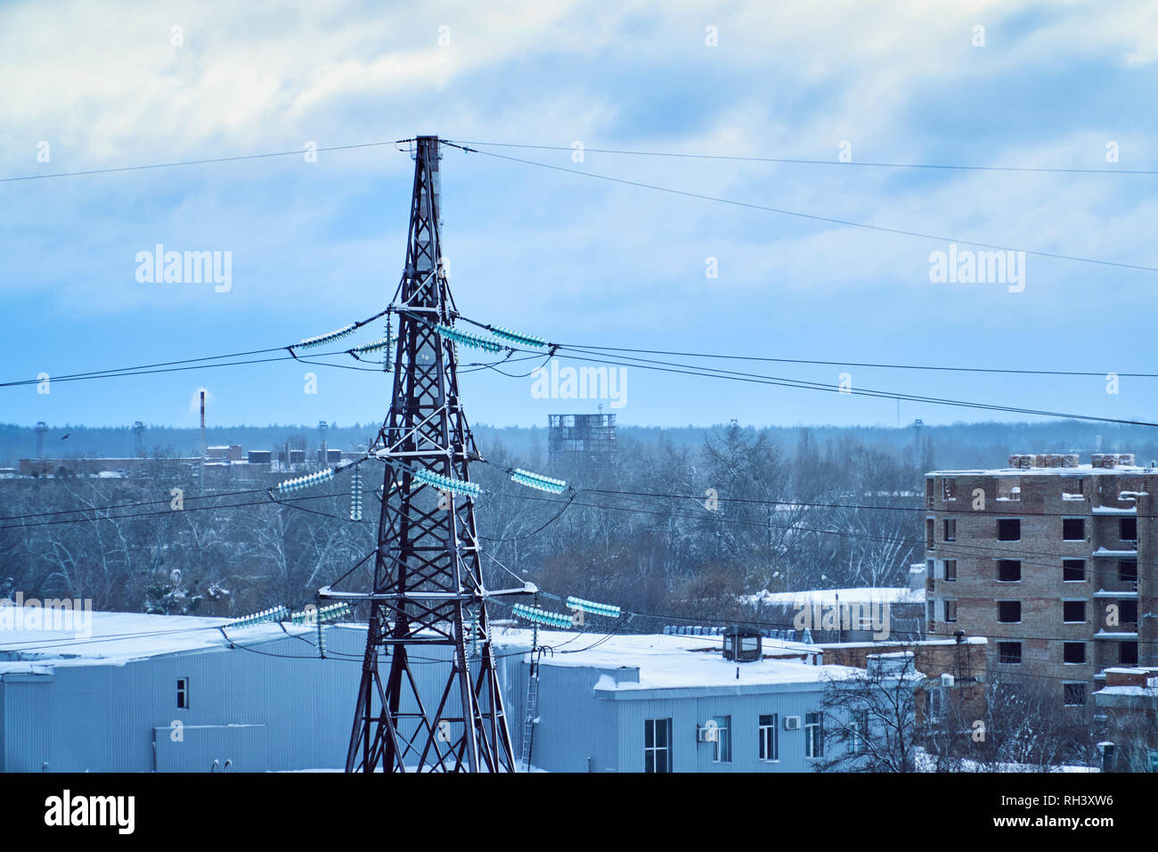 Power Transmission Line Turm gegen den blauen Himmel und Wolken mit schneebedeckten Hochspannungs-Isolatoren. Winter Stockfoto