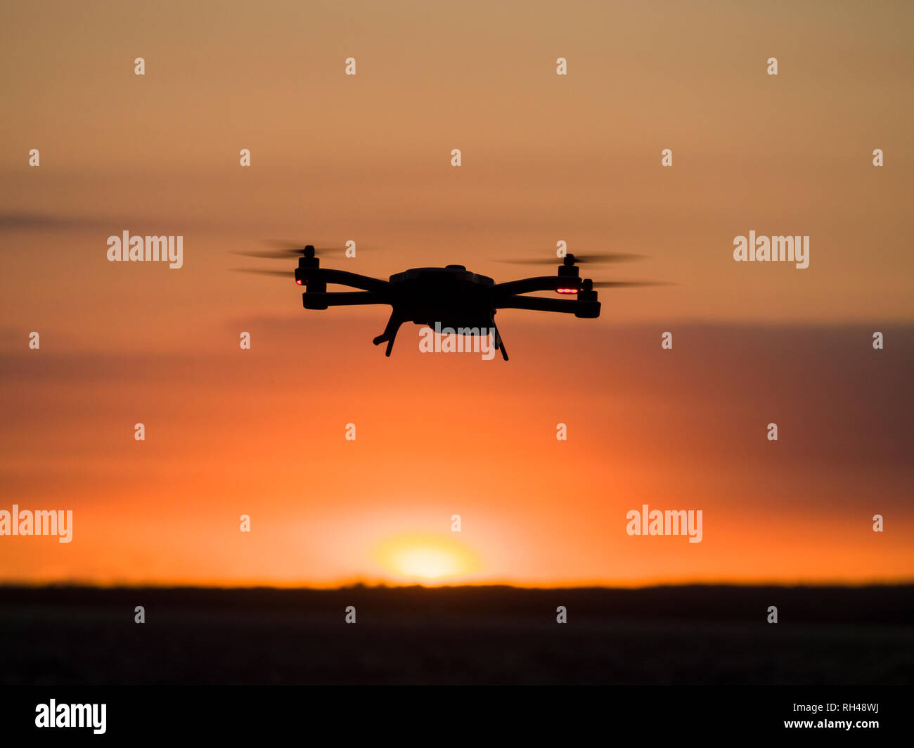 Brummen bei Sonnenuntergang: Eine kleine Drohne schwebt über dem Ottawa River so wie die Sonne untergeht. Stockfoto