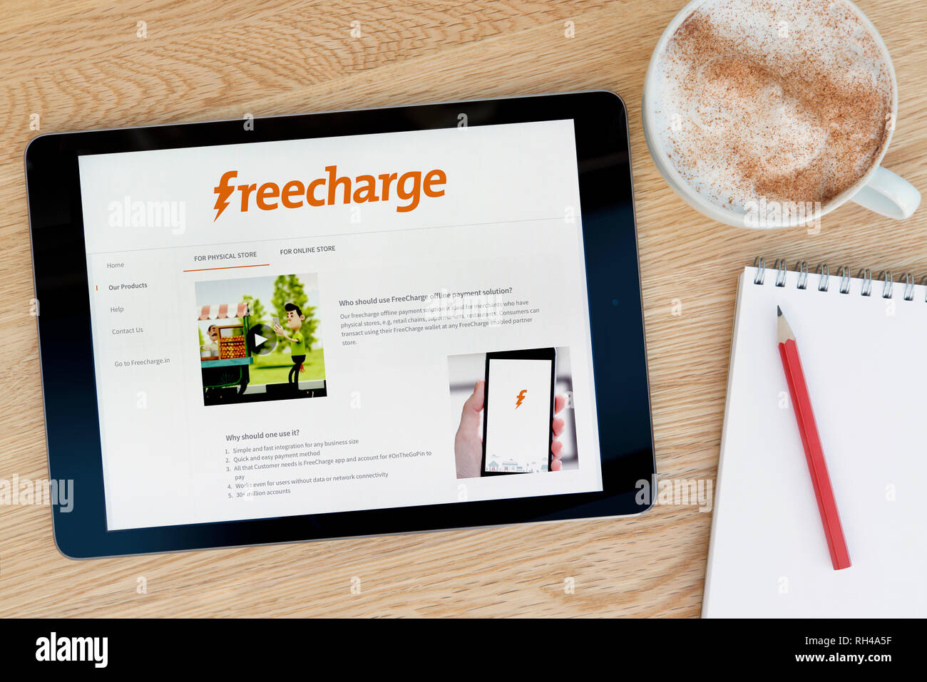 Die Freecharge website Funktionen auf einem iPad Tablet Gerät, das auf einem Tisch liegt neben einem Notizblock (nur redaktionelle Nutzung). Stockfoto