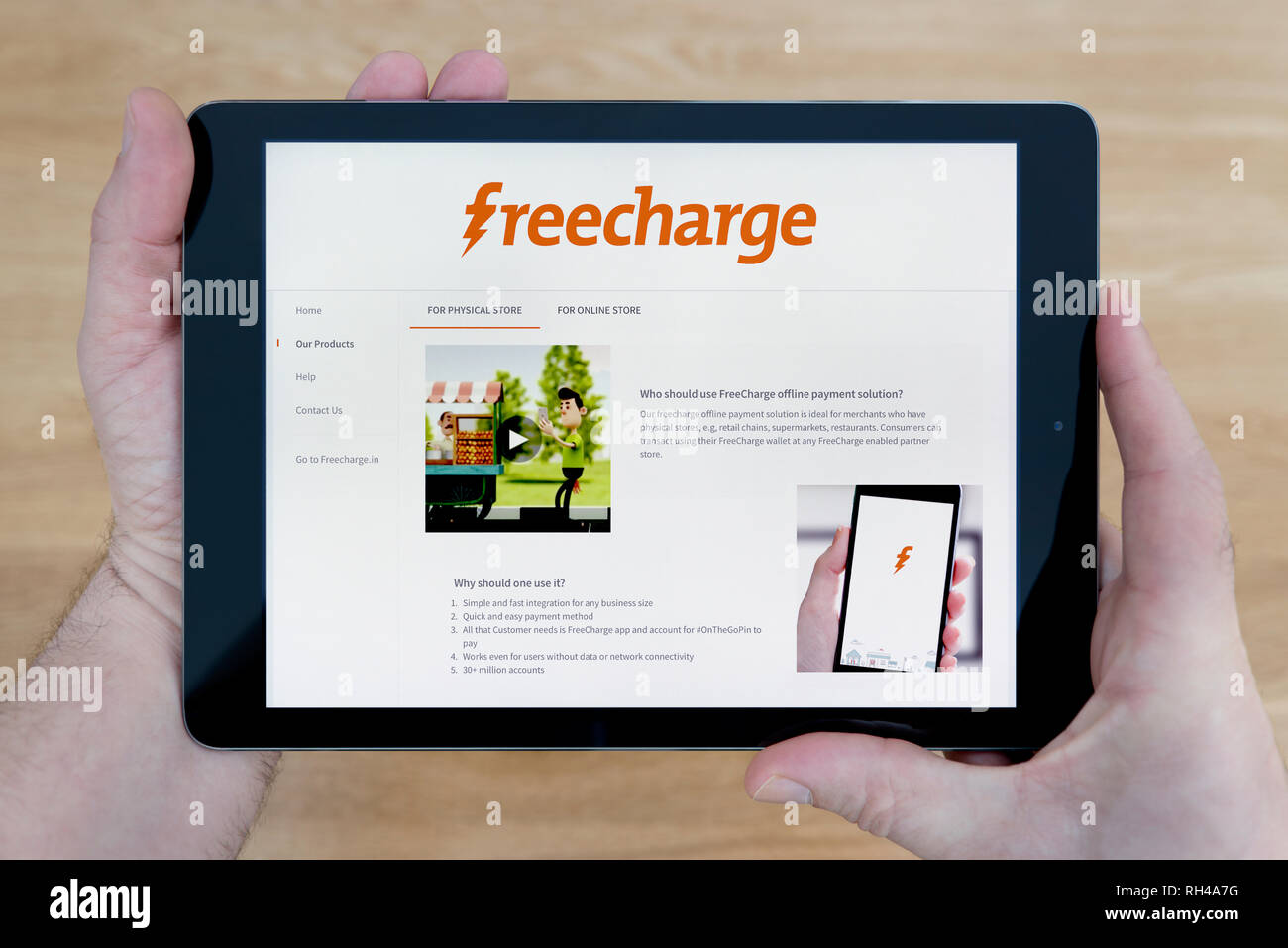 Ein Mann schaut den Freecharge Website auf seinem iPad tablet device, Schuß gegen einen hölzernen Tisch top Hintergrund (nur redaktionelle Nutzung) Stockfoto