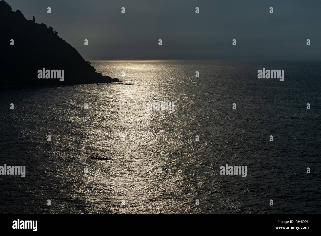 Leuchtturm von San Sebastian bei Sonnenuntergang Hintergrundbeleuchtung und reflektierte Sonnenlicht auf dem Meer Stockfoto