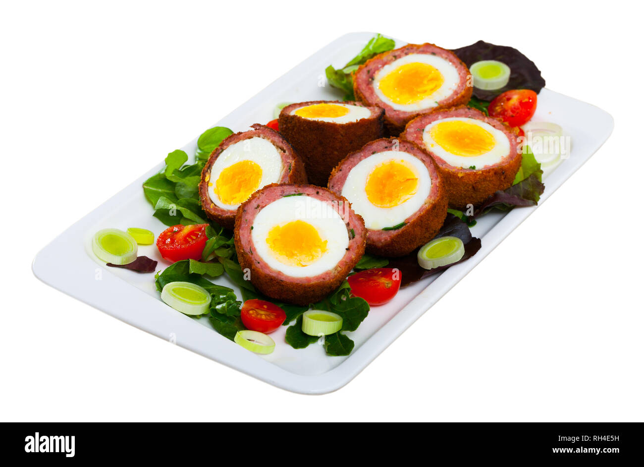 Traditionelle britische Picknick Essen - lecker Scotch Eier schnitt in Hälften mit Gemüse Salat von grünen und Tomaten. Auf weissem Hintergrund Stockfoto
