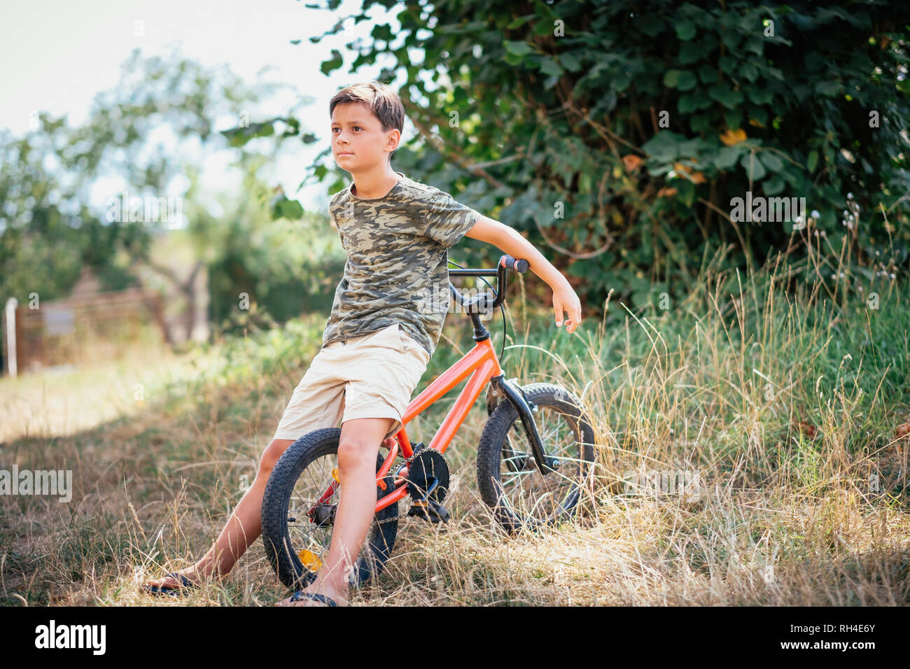 Junge mit dem Fahrrad in Gras Stockfoto
