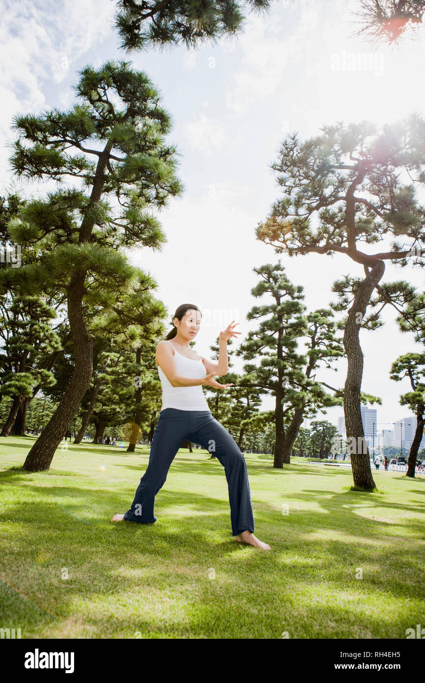 Frau üben von Tai Chi im sonnigen Park, Tokio, Japan Stockfoto