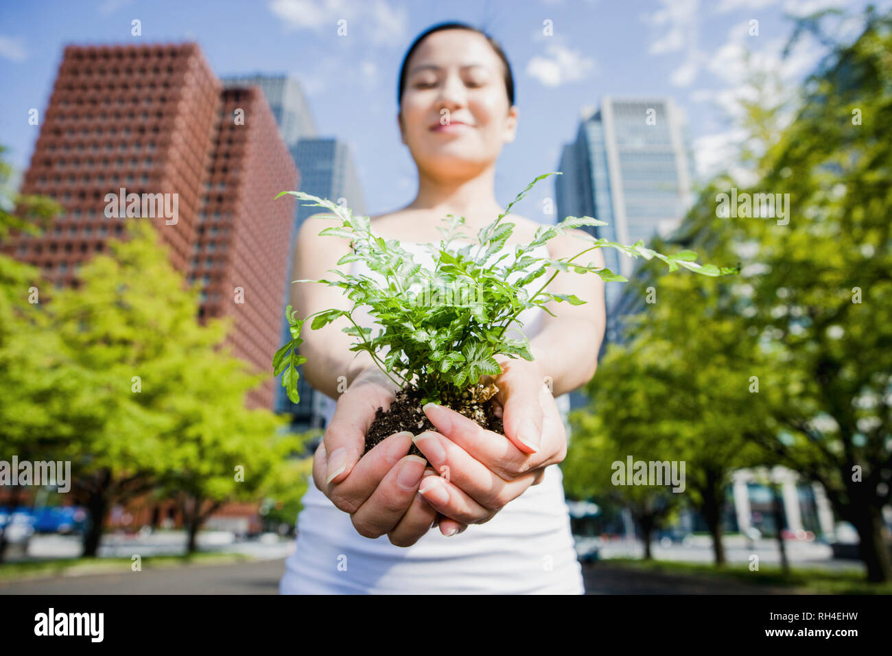 Portrait Frau mit grünen Setzlingen in der sonnigen Stadt Tokio, Japan Stockfoto