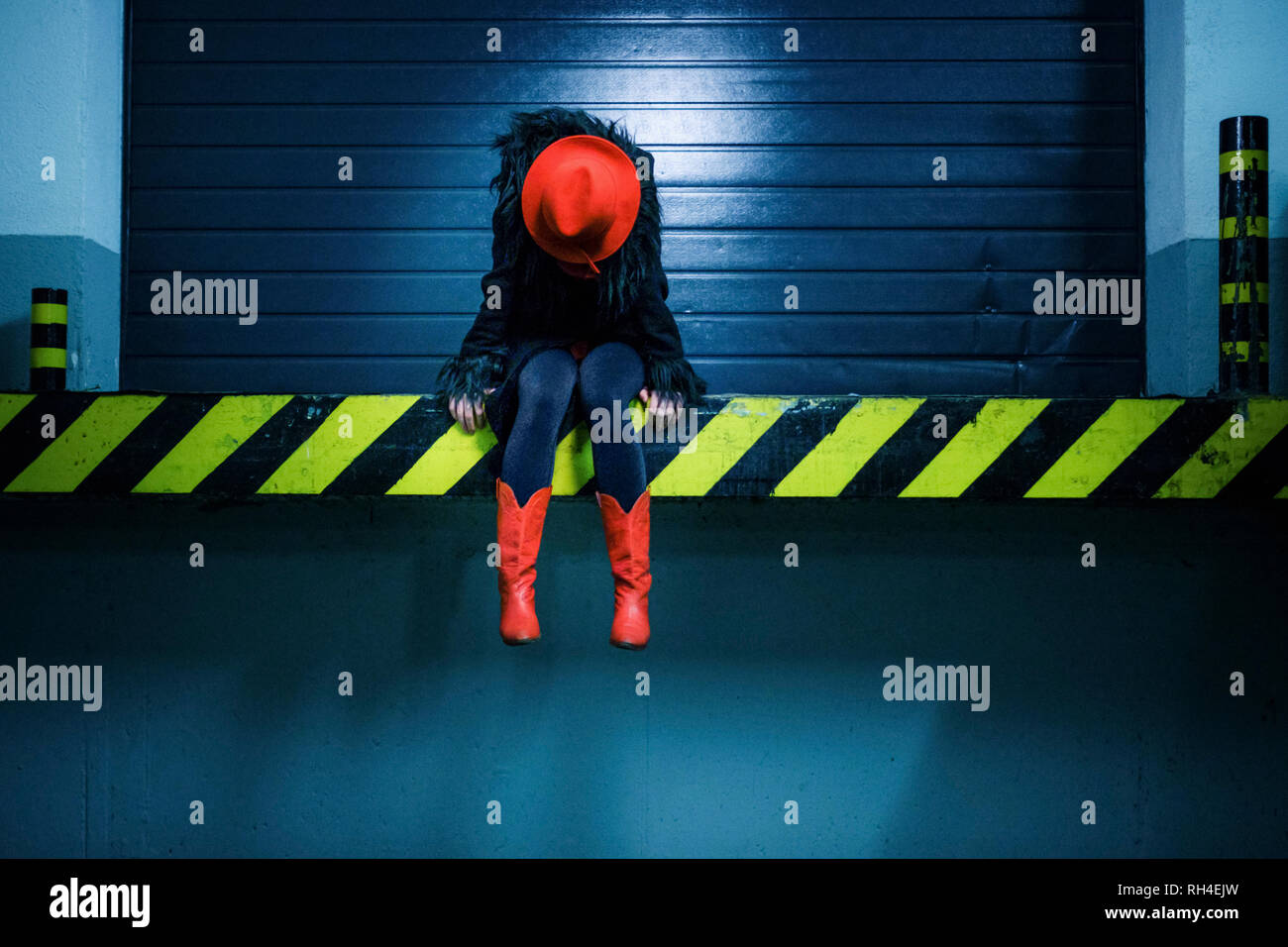 Junge Frau in Rot Cowboy Stiefel an der Kante der laderampe Sitzen Stockfoto