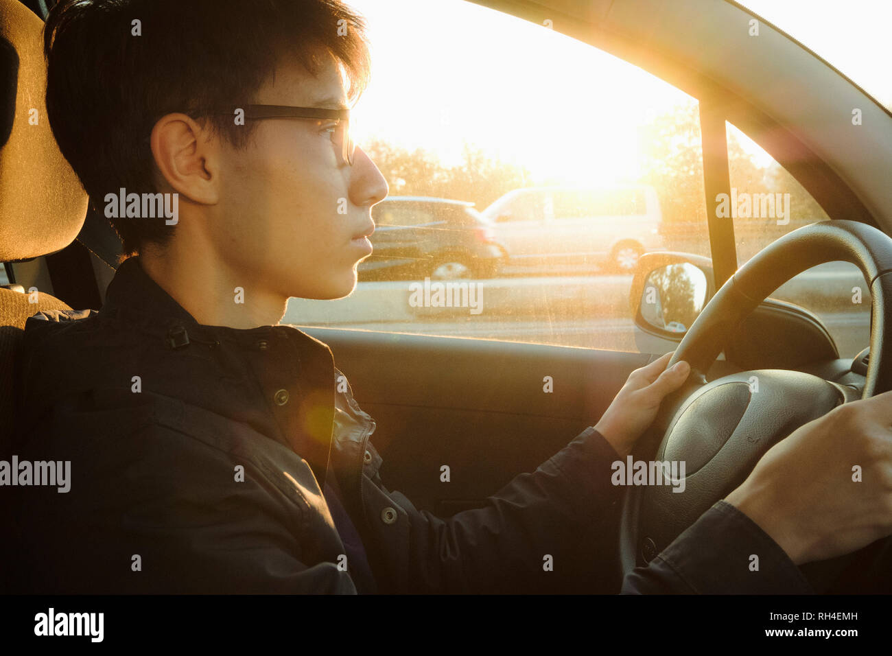 Junger Mann fährt Auto auf Sunny Road Stockfoto