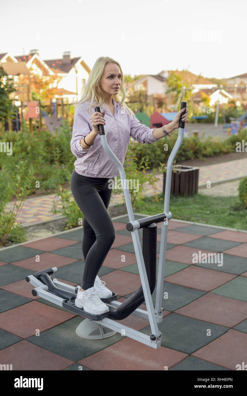 Passende Frau mit elliptischen Maschine auf der Terrasse Stockfoto