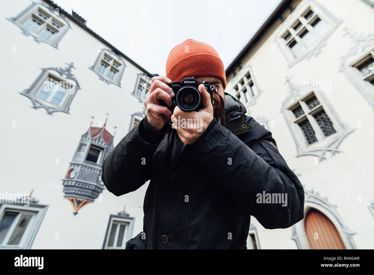 Füssen, Deutschland - Dezember 2018: Mann in Orange hat Bilder im Hinterhof des Hohen Schloss entfernt. Stockfoto