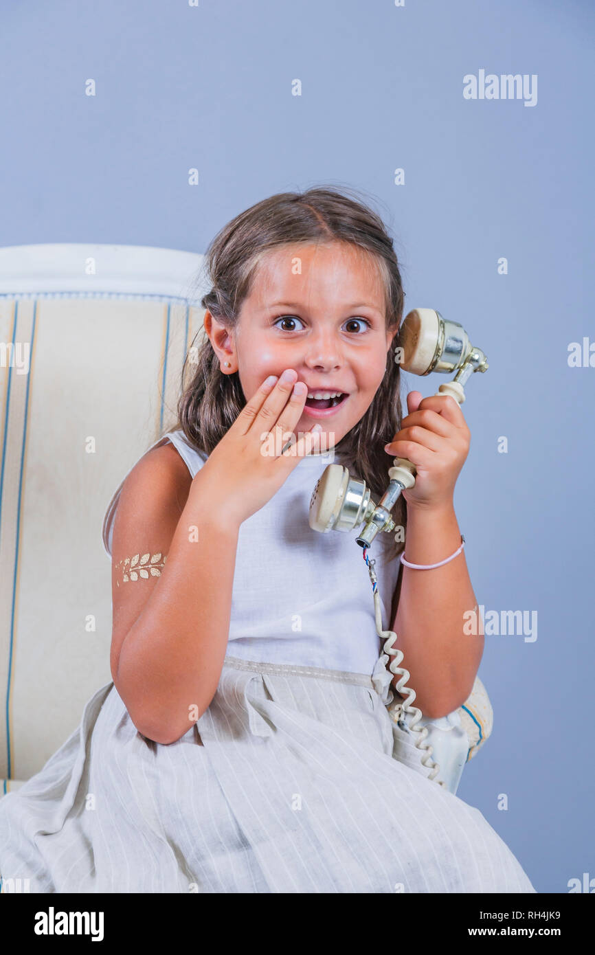 Mädchen im Kleid im Gespräch mit alten Telefon mit überraschten Gesicht Stockfoto