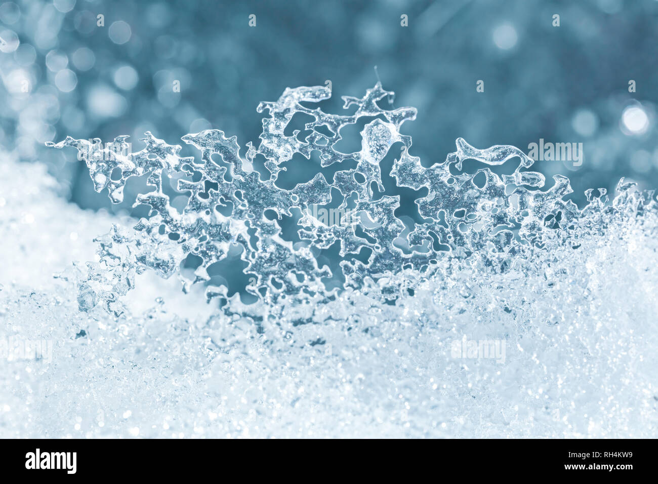 Schmelz vereisten Schnee Textur closeup gegen blaue Lichter Hintergrund verschwommen Stockfoto