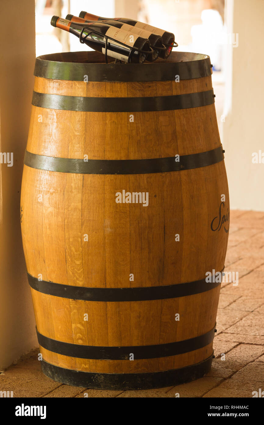 Eiche Weinfass oder Mehrwertsteuer als Einrichtung im Innenbereich auf einem Weingut und Anzeige von 3 Flaschen oder Rotwein Paarl, Cape Town, Südafrika Stockfoto