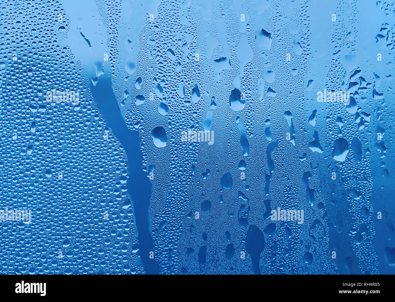 Große und feine Wassertropfen auf blauem Glas Stockfoto