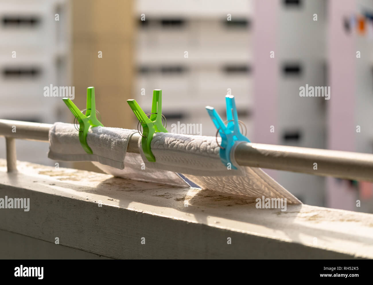 Kunststoff Kleidung Clips auf das Geländer. Wäscheservice Haken mit Waschlappen. Apartment Gebäude im Hintergrund. Stockfoto