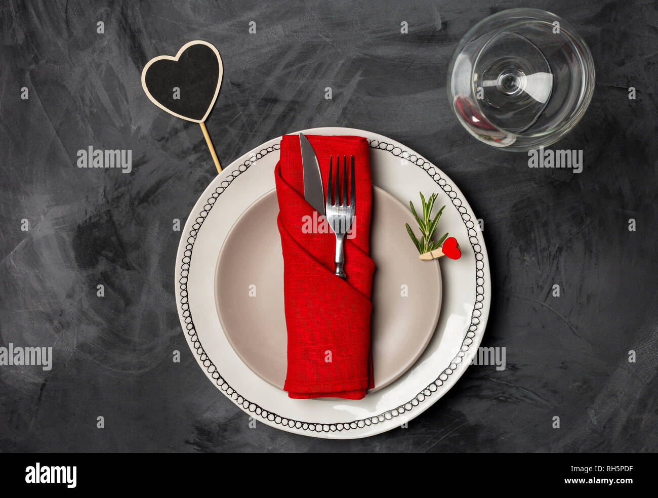 Servierteller für den Valentinstag oder ein romantisches Abendessen mit zwei Teller, Gabel, Messer rot Serviette, Rosmarin und Pin, Glas für Wein und herzförmige Ort Stockfoto