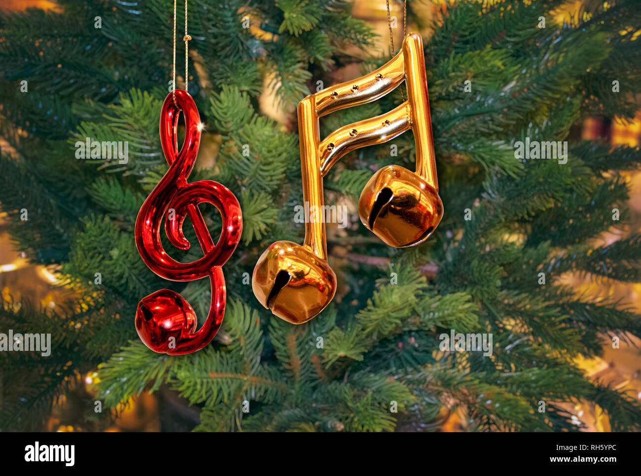 Glänzendes Rot Violinschlüssel Ornament und Gold Noten mit Glocken auf grüner Weihnachtsbaum Stockfoto