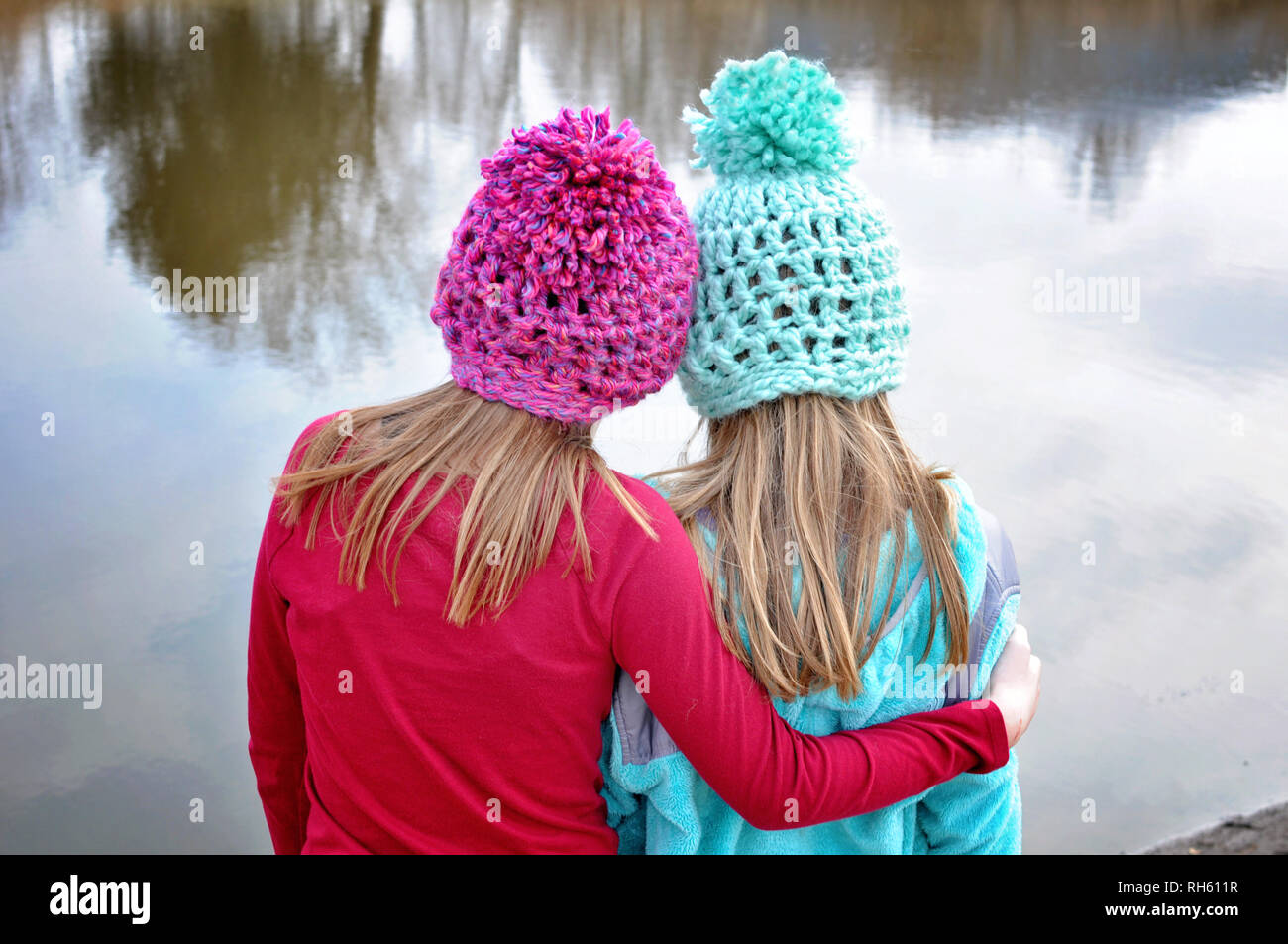 Zwei Mädchen mit gehäkelte Hüte umarmen Stockfoto