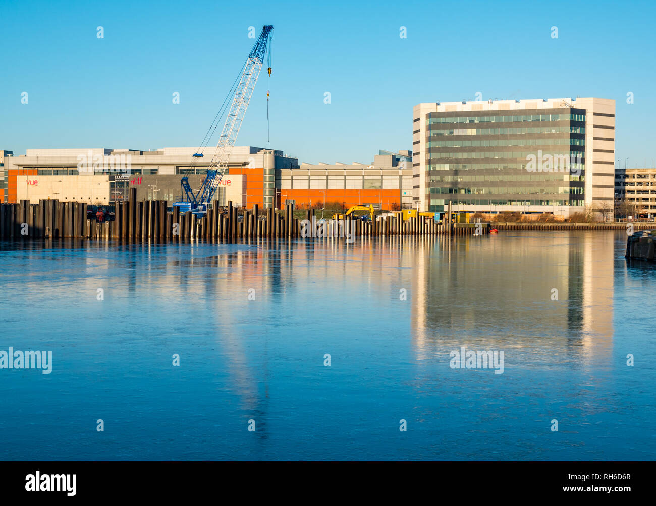 Leith, Edinburgh, Schottland, Großbritannien, 1. Februar 2019. UK Wetter: ungewöhnliches Phänomen eines gefrorenen Wasser in Albert Dock Bassin in Leith Harbour mit Gebäude am Ocean Terminal und der Baustelle mit Kran in der eisigen Oberfläche des Wassers wider Stockfoto