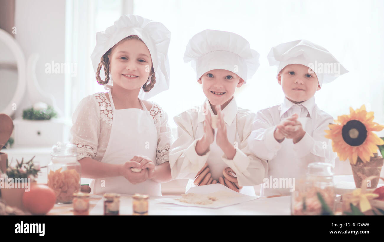 Glückliche Kinder in Form einer Küchenchef leckere Mahlzeiten zubereiten Stockfoto