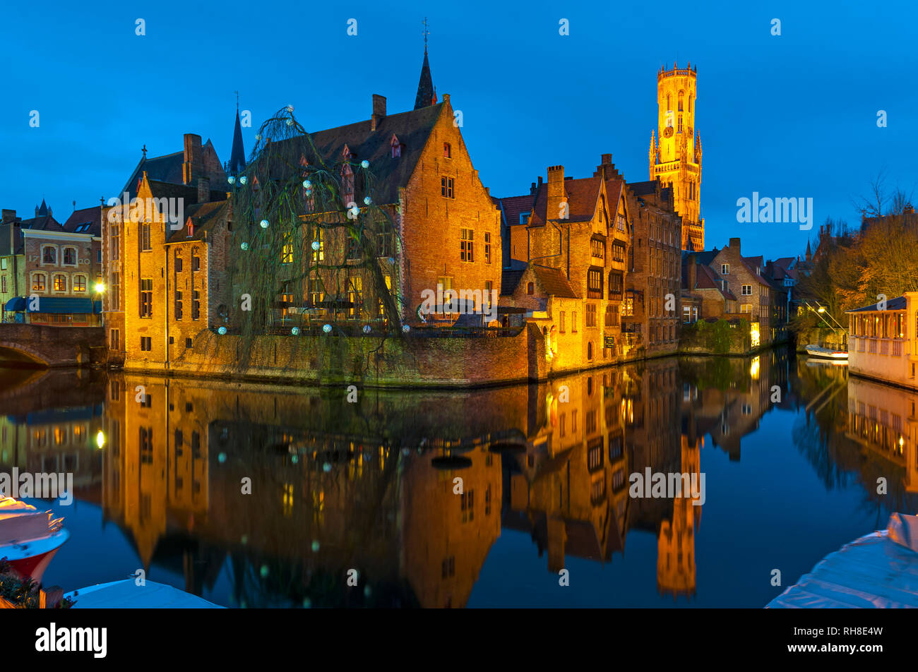 Lange Exposition von den Brügger Kanälen vom Rozenhoedkaai mit einer Reflexion auf die beleuchtete Belfried und mittelalterliche Architektur, Westflandern, Belgien. Stockfoto
