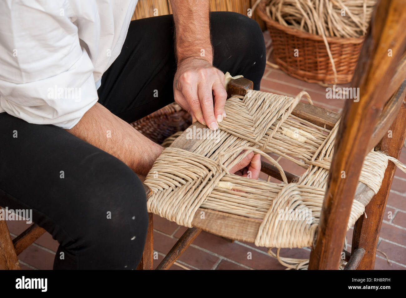 Ein mender von Stühlen während der Reparatur ein Stuhl Sitz mit Stroh. Stockfoto