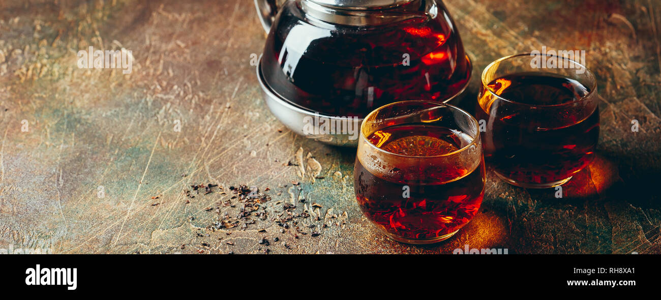 Glas transparent Teekanne und zwei Glas Tassen mit schwarzem Kaffee auf einem dunklen Tabelle Stockfoto