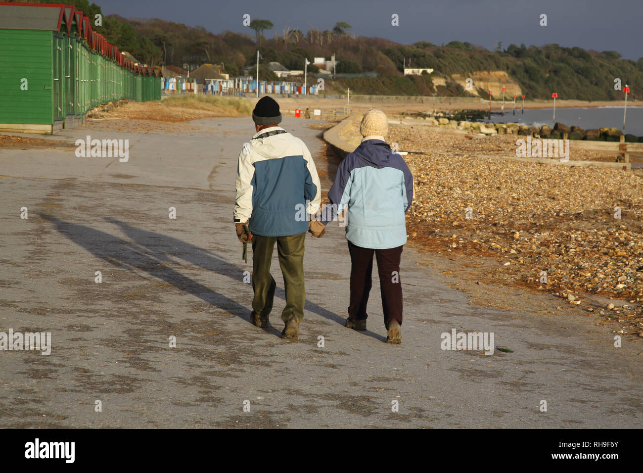 Zwei Menschen zu Fuß entlang der Küste von mudeford Hampshire an der Küste von England Stockfoto