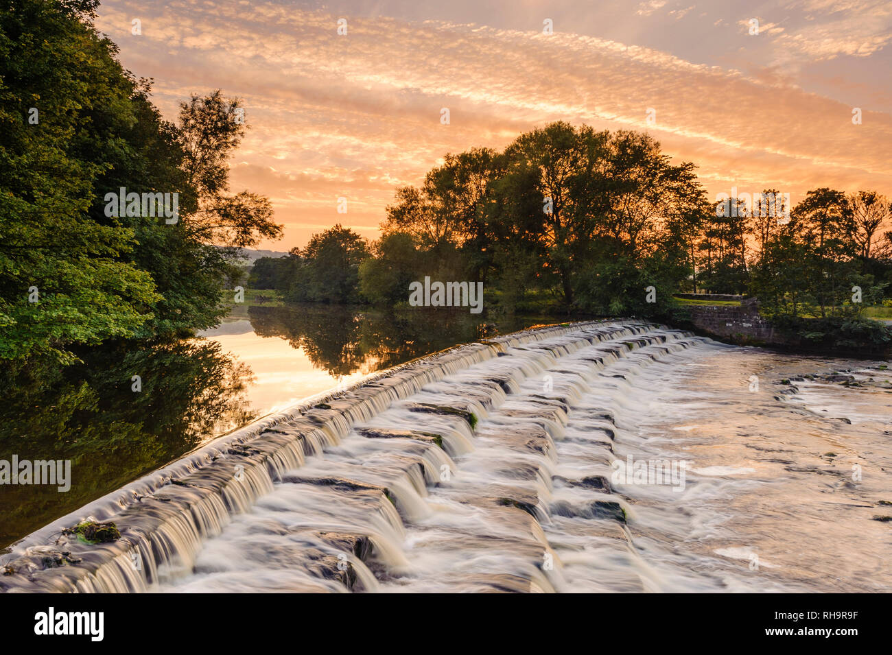 Einen malerischen Sonnenuntergang Himmel über ländliche Landschaft (Wasser sanft fließende Wehr Schritte) - River Wharfe, Burley in Bösingen, Yorkshire, England, UK. Stockfoto