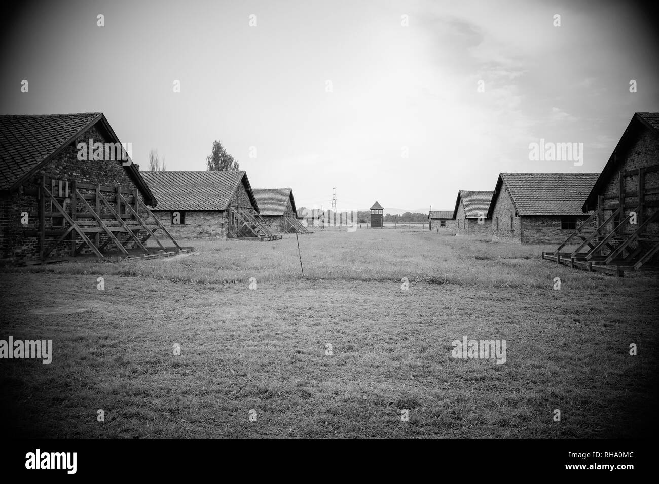 Häftlingshütten, in denen Juden aufbewahrt wurden, bevor sie in die Gaskammern und den Wachturm im Hintergrund gingen Stockfoto