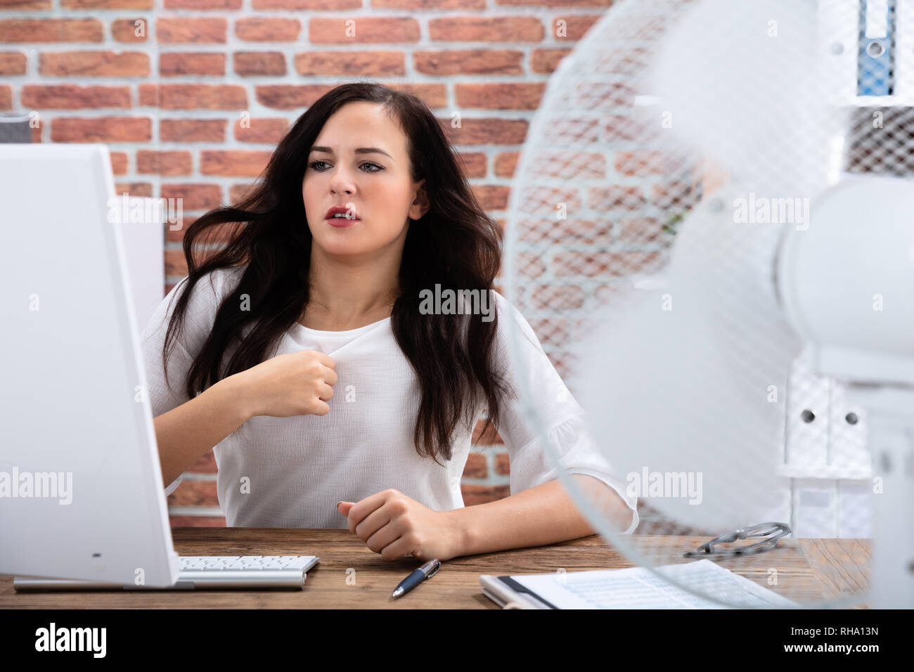 Junge Geschäftsfrau Kühlung sich Vor Ventilator bei heißem Wetter Im Büro Stockfoto