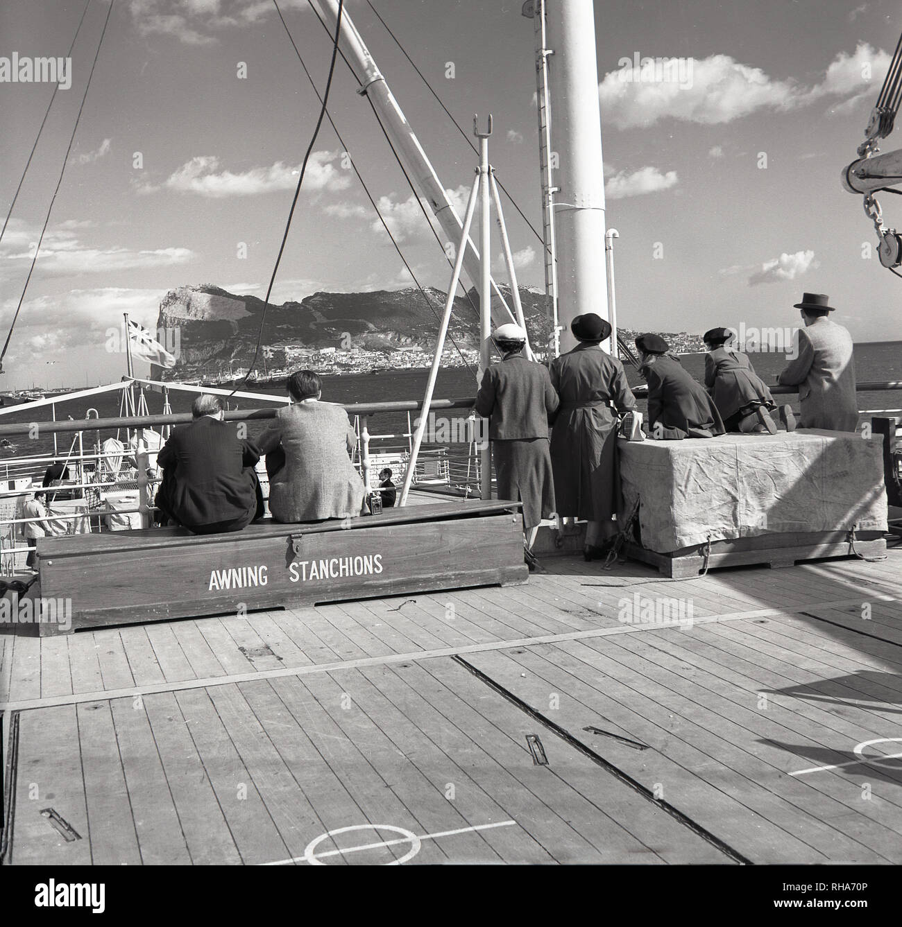 1950er Jahre, am Vorgewende oder Felsen von Gibraltar nähern, Passagiere an Deck eines Union - Schloss steamship sitzen an Markise rungen, die Ankunft. Auf den ersten settledby die Mauren und dann Spanien, das Outpost an der spanischen Südküste der Britischen 1713 abgetreten wurde und bleibt bis heute ein Britihs Überseegebiet. Die 462 m hohe Kalkstein Ridge (der Fels) ist die berühmte Sehenswürdigkeit. Stockfoto