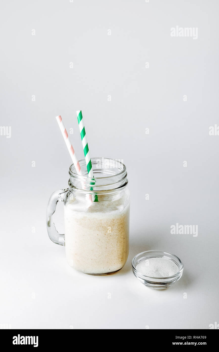 Ein Glas Protein mit Vanille und Pulver auf weißem Hintergrund Stockfoto