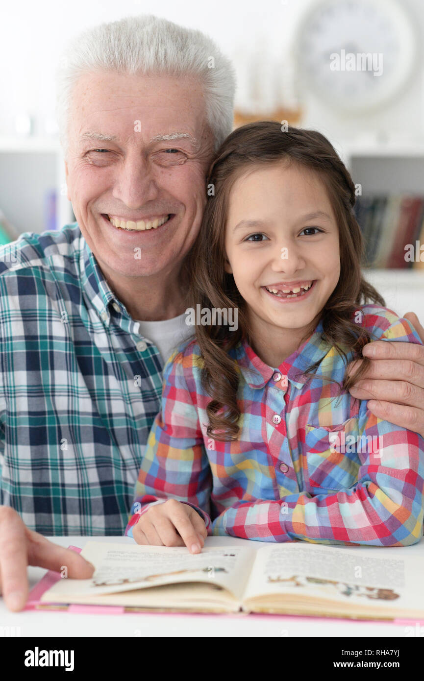 Kleines nettes Mädchen mit Großvater lesen Buch Stockfoto