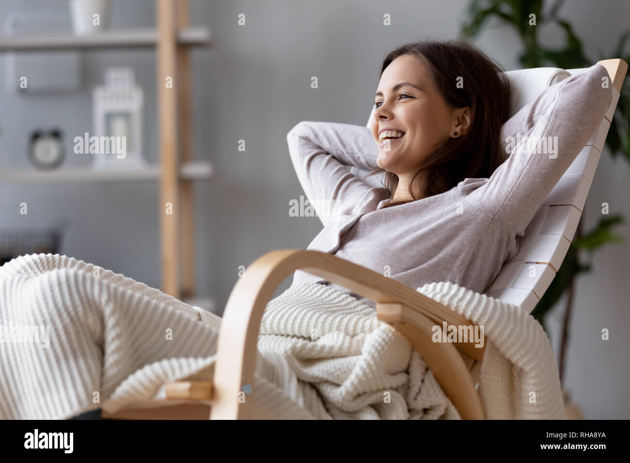 Happy tausendjährigen Frau lachend auf komfortable Holz Schaukelstuhl Stockfoto