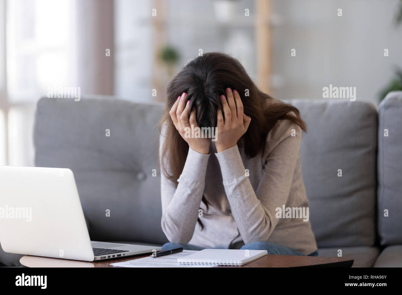 Verärgert Frau mit Kopf in den Händen frustriert sitzt in der Nähe von Laptop Stockfoto