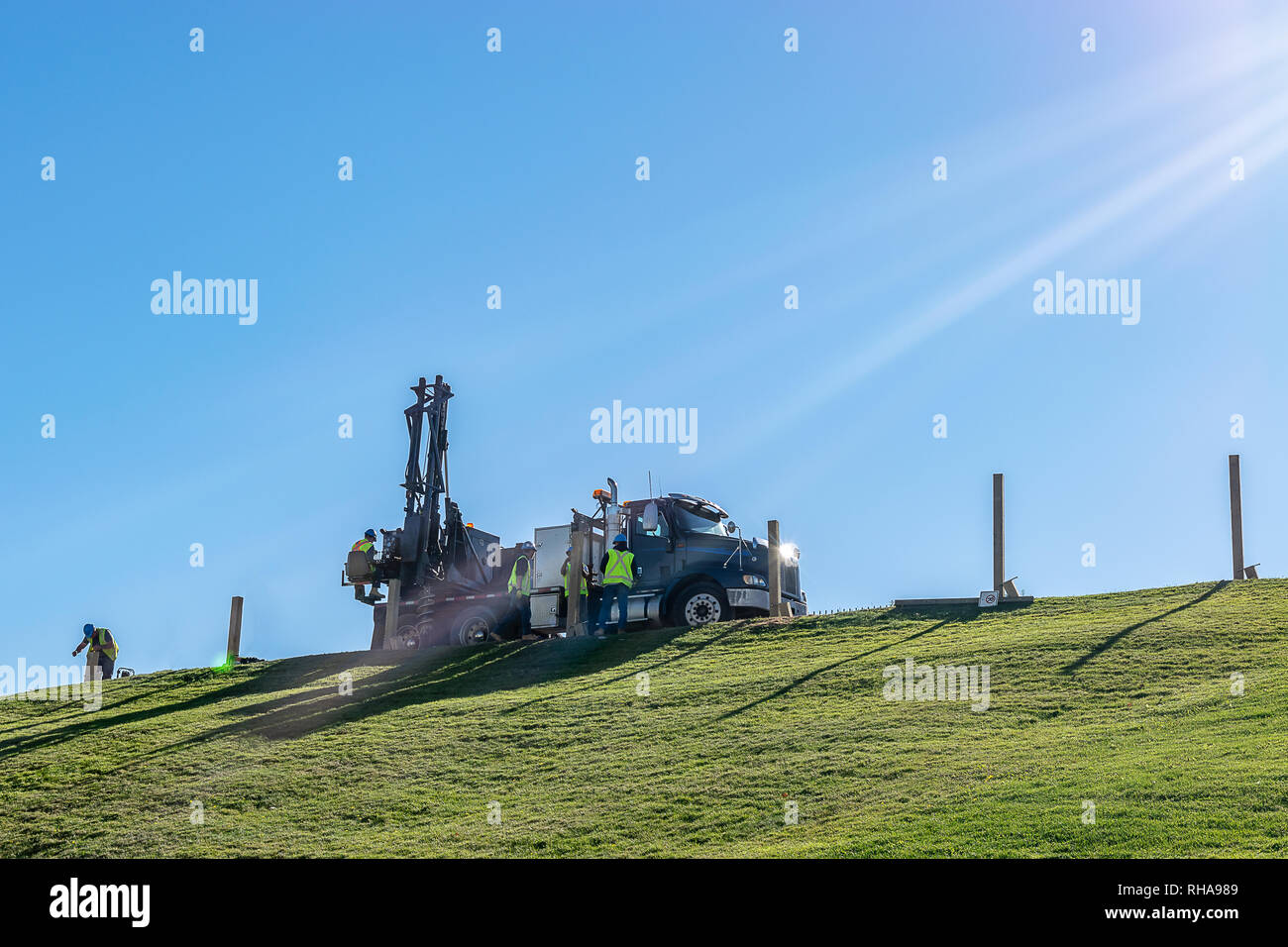 Kaukasische männlichen Ingenieure arbeiten und Bedienen eines hydraulischen Teleskop Stapler Schnecke Kran Bohrgerät auf einem Hügel, an einem sonnigen Tag montiert. Stockfoto